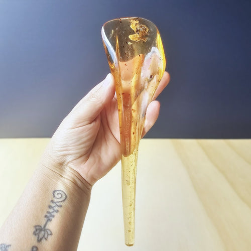 Hand holding a translucent amber-colored object against a neutral background