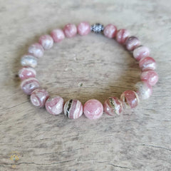 Rhodochrosite bracelet with pink and white striped beads, displayed on a wooden surface.